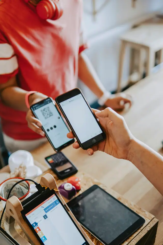 Two hands holding smartphones together to make a contactless payment at a shop counter