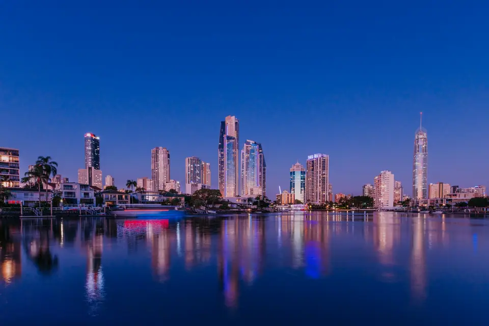 Illuminated city skyline reflected in calm water at deep blue twilight